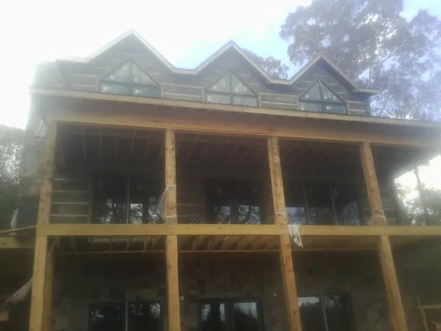 Dormers and porch framing on a large log home under construction — Roof Coating work by our crew in Colchester