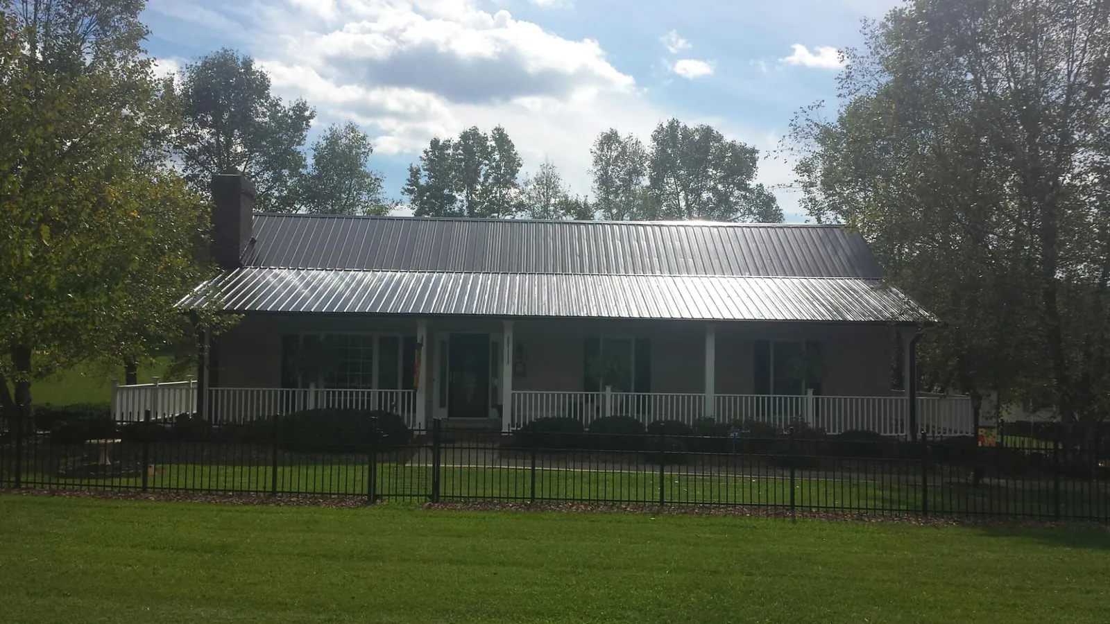 Gray metal roof on a brick ranch with a full width front porch — Gutter Guard Installation work by our crew in Colchester